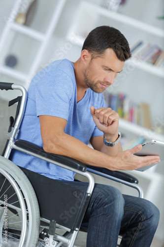 disabled man in wheelchair using digital tablet at home