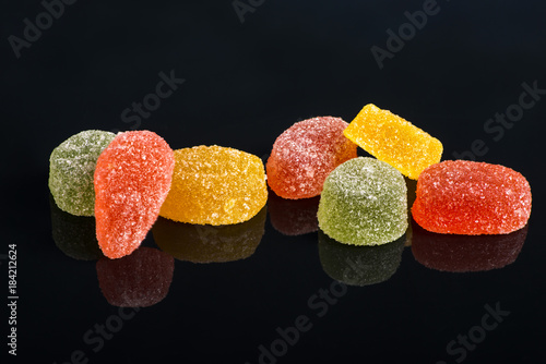 Photos Seven multi-colored fruit-paste sweets  on the black reflecting surface