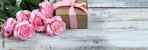Six pink roses and giftbox on rustic white wooden background