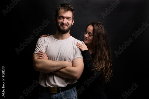 Portrait of a young beautiful cheerful couple on a black background.