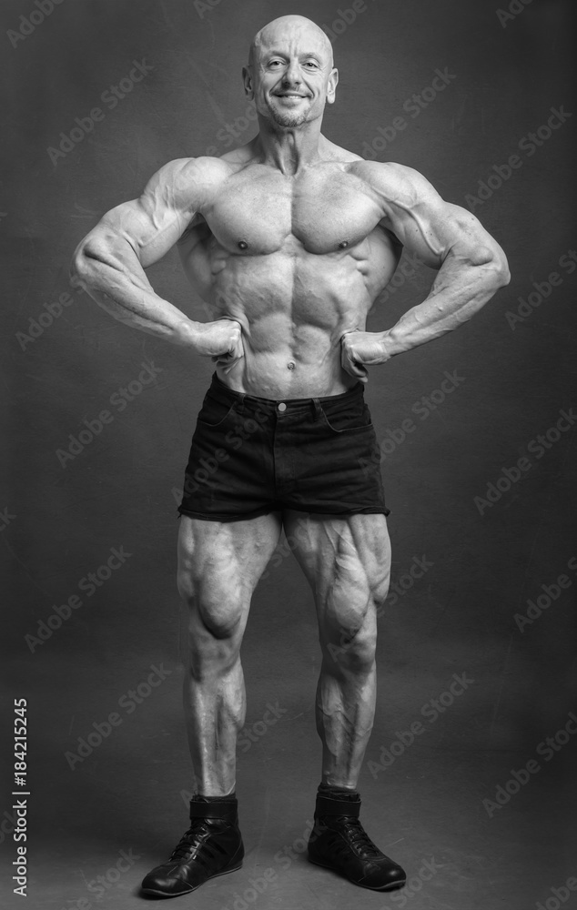 Athlete in front lat spread pose. Bodybuilder showing muscles on studio background