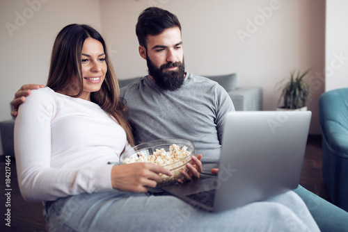 Couple watching a movie on laptop in their living room