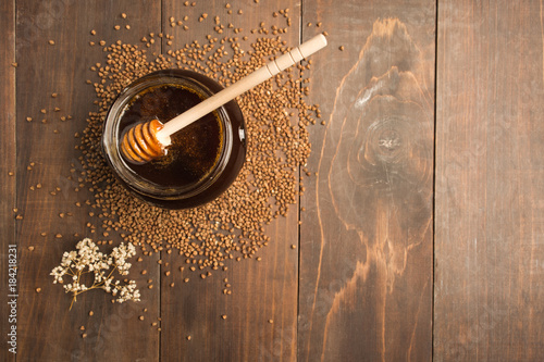 Buckwheat honey over brown wooden background