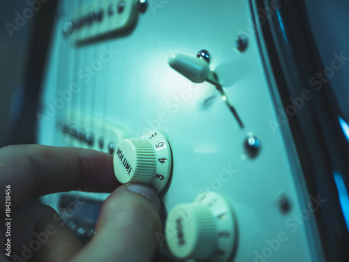 macro shot of man changing volume on the electric guitar photo