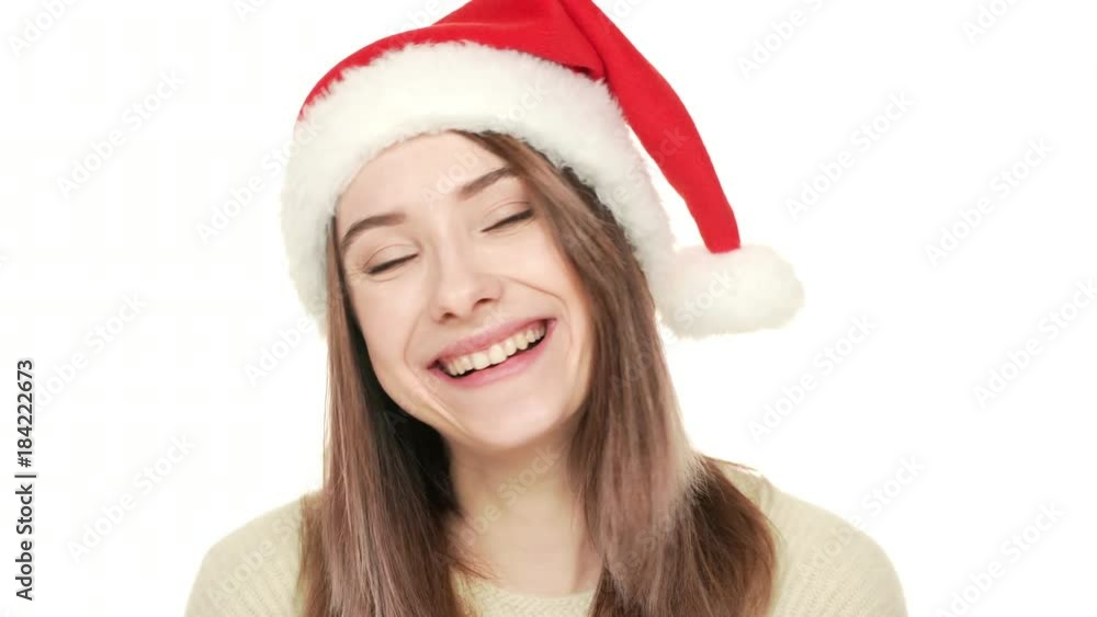 Headshot of contented caucasian woman being happy with Christmas holidays wearing Santa Claus red hat smiling while posing over white background. Concept of emotions Headshot of contented caucasian woman being happy with Christmas holidays wearing Santa Claus red hat smiling while posing over white background. Concept of emotions