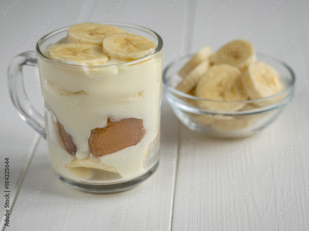 Glass bowl with pieces of banana and banana pudding in a Cup on a white table. Glass bowl with pieces of banana and banana pudding in a Cup on a white table.