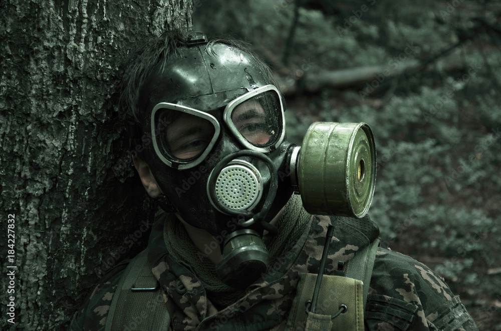 soldier in a gas mask in a wet forest soldier in a gas mask in a wet forest