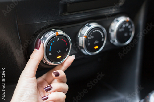 Woman turning on car air conditioning system switch..
