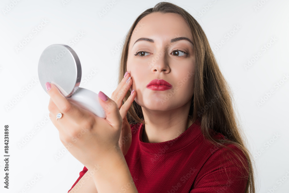 young beautiful woman doing make-up isolated on white background. she looks looks in the mirror young beautiful woman doing make-up isolated on white background. she looks looks in the mirror