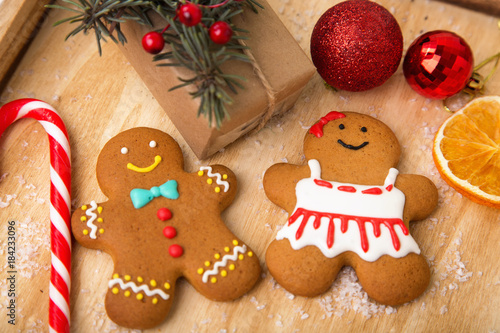 Couple gingerbreads. Christmas homemade gingerbread cookies on wooden table. Gingerbread man, candy, lollipop, dried orange, candied fruit - a traditional Christmas treat.