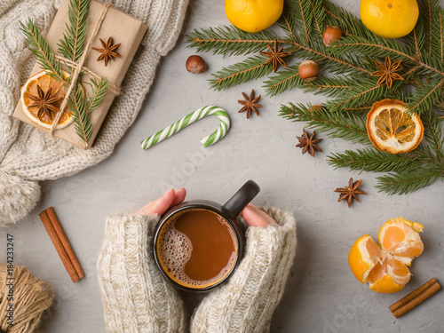 Winter hot drink female hands in a sweater holding a Cup of hot chocolate on a gray concrete background tangerines scenery photo