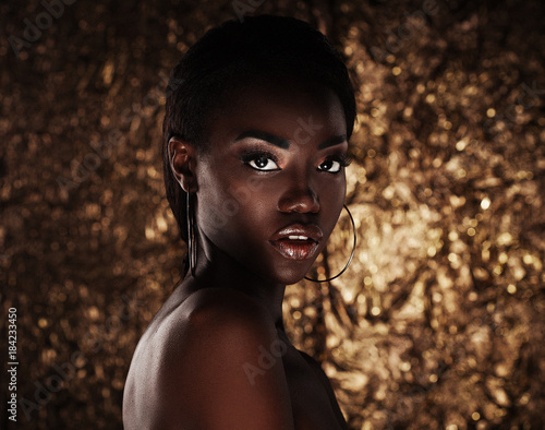 portrait of sensual young african woman against golden background