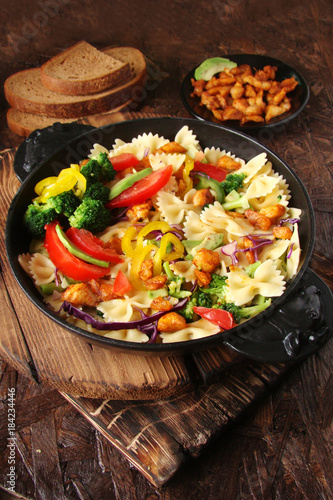 Farfalle pasta with slices of grilled chicken, sweet peppers, avocado, cabbage, broccoli, tomatoes and red cabbage