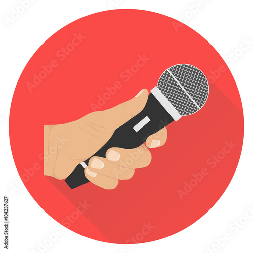 The hand holds the microphone. Microphone in hand on a red background with a shadow.