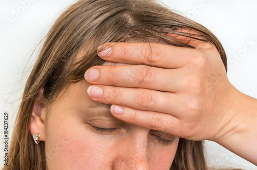 Woman with headache is holding her aching forehead