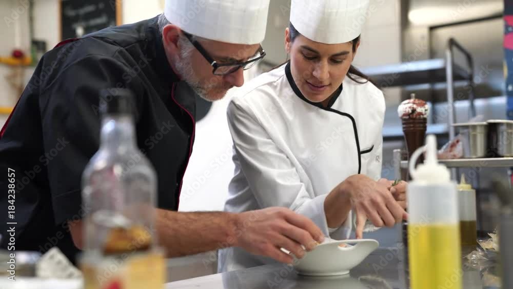 Professional cook chefs in kitchen improving dish composition Professional cook chefs in kitchen improving dish composition