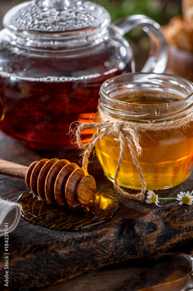jar of honey with honey dipper close-up and hot teapot on dark wooden board
jar of honey with honey dipper close-up and hot teapot on dark wooden board