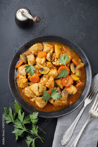 Goulash traditional Hungarian dish. Stew with pepper and tomato sauce in ceramic plate on dark black stone or concrete background. Selective focus. Top view.