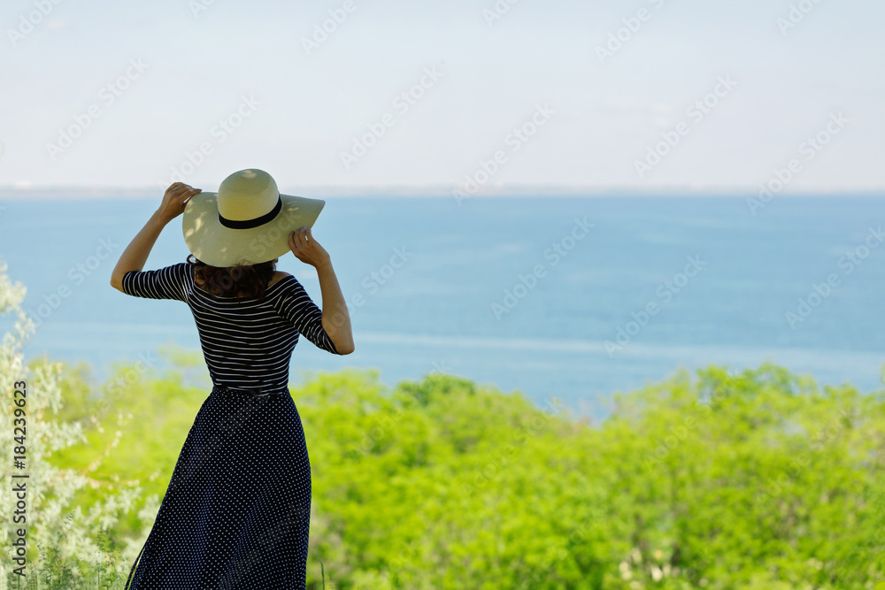 Young woman in a long dark blue skirt on the waterfront near the sea.
