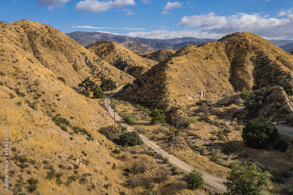 Dirt path curves through hills in the southern California wilderness of Angeles National Forest.