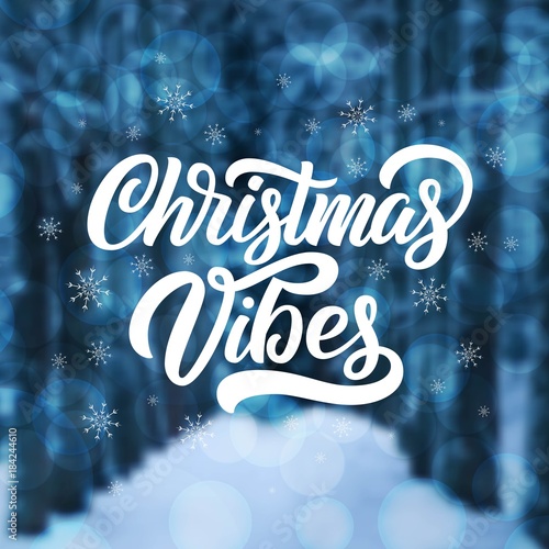 Winter forest evening blue defocused background with snowflakes and Christmas Vibes hand lettering. Vector festive holidays design.