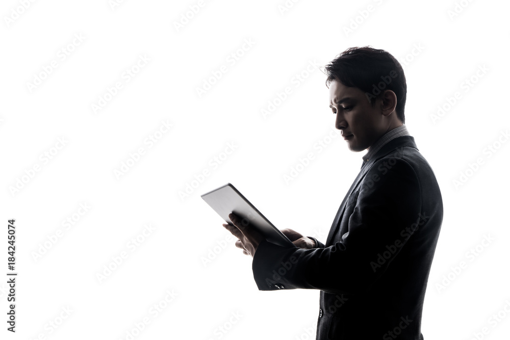 Silhouette of businessman looking tablet PC.