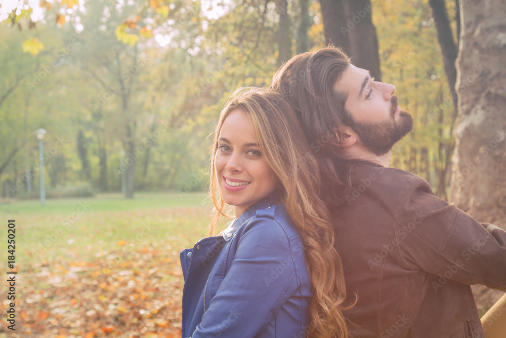 Cute couple sitting on a bench in park filled with autumn colors. Cute couple sitting on a bench in park filled with autumn colors.