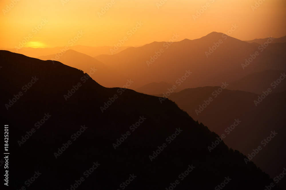 Natural background with mountains at the sunset or sunrise in yellow and orange colours