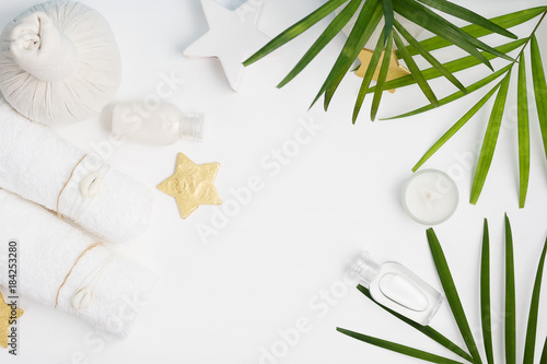 Flat lay top view spa background: thai massage bag, towels and palm leaves on white background. Healthy lifestyle. Text space