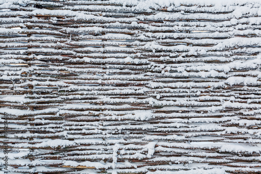 Fototapeta premium The texture of the fence of wicker, covered with snow.