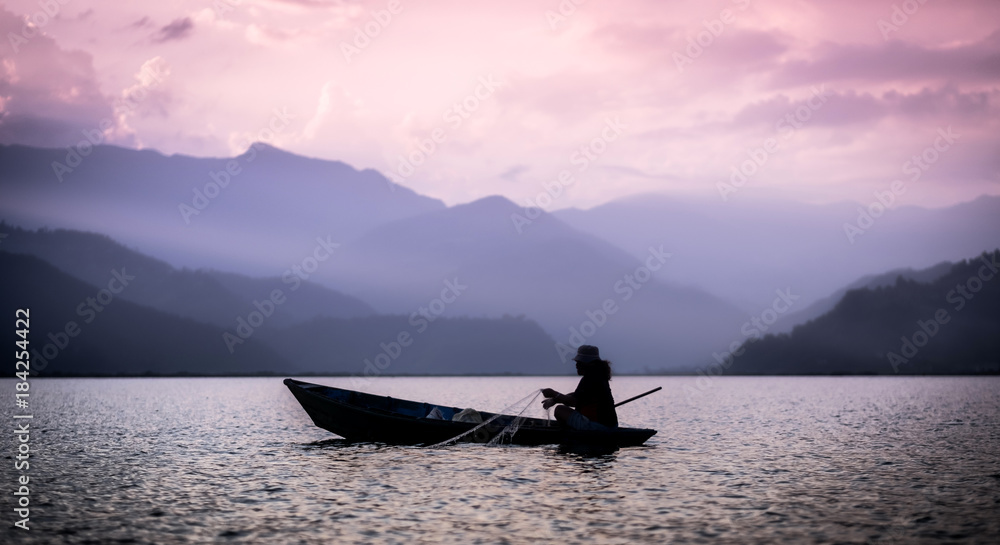 Lonely fisherman on the boat fishing in Phewa lake, Nepal Lonely fisherman on the boat fishing in Phewa lake, Nepal