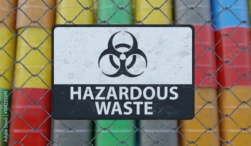 Hazardous waste sign on chain link fence. Oil barrels in background. 3D rendered illustration.