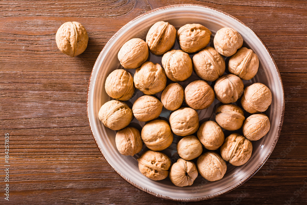 Plate with walnuts on a ceramic table. Top view Plate with walnuts on a ceramic table. Top view