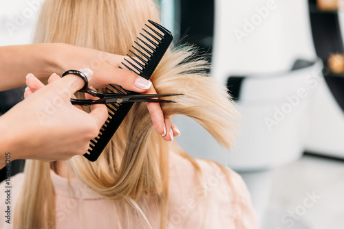 Papier peint Image recadrée du coiffeur coupe les extrémités des cheveux blonds