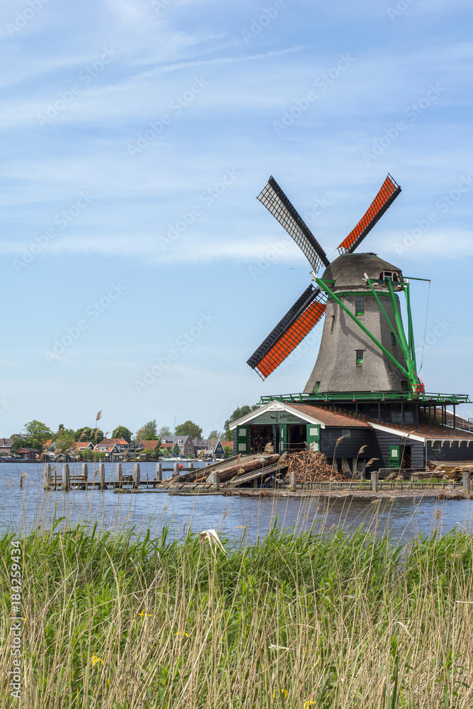 One grey mill with orange wings near the water in  Zaanse Schans (Netherlands)