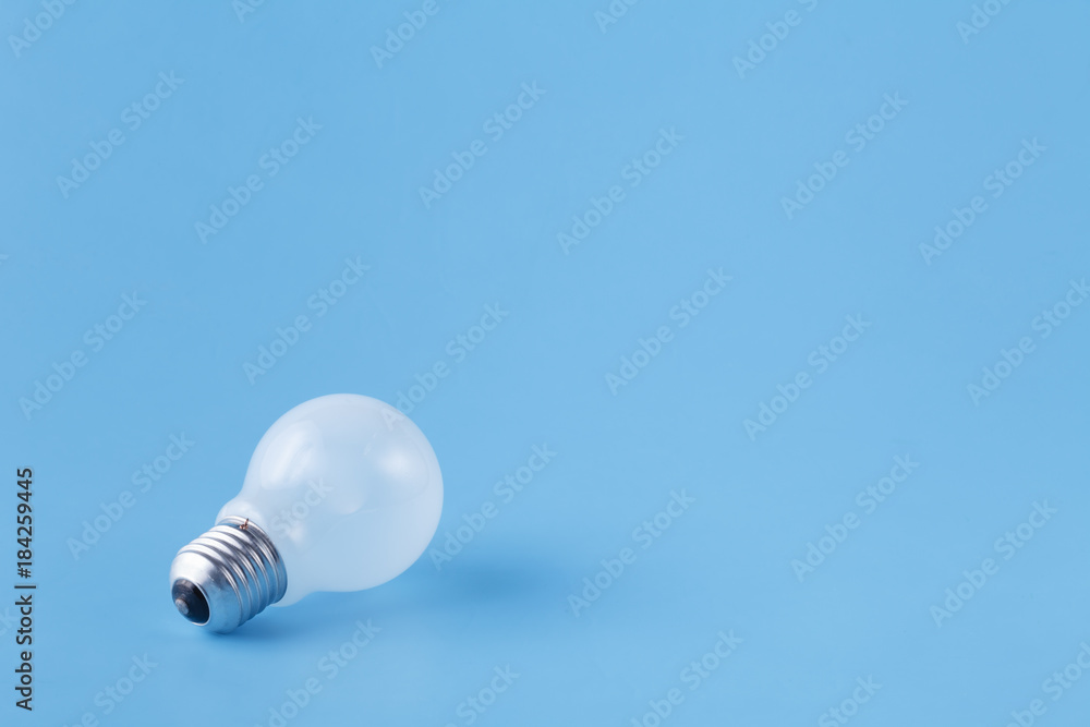 One light bulb on plain blue background One light bulb on plain blue background
