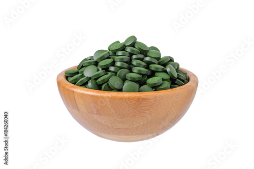 organic spirulina and chlorella pills in a wooden bowl isolated on white photo