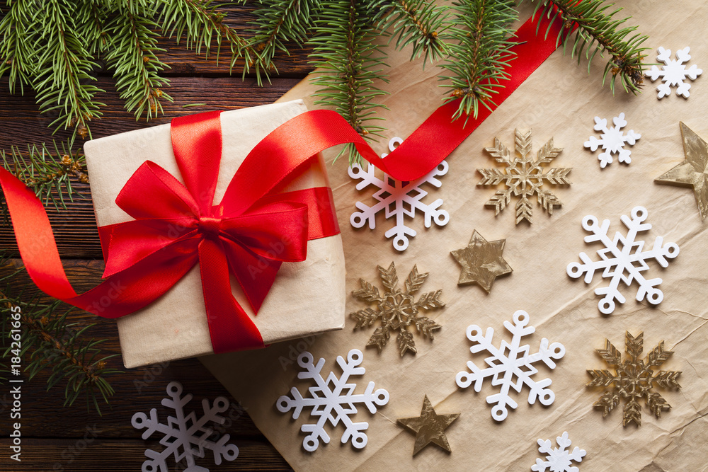 Christmas gift box, spruce tree, snowflakes and stars on paper and wooden background Christmas gift box, spruce tree, snowflakes and stars on paper and wooden background