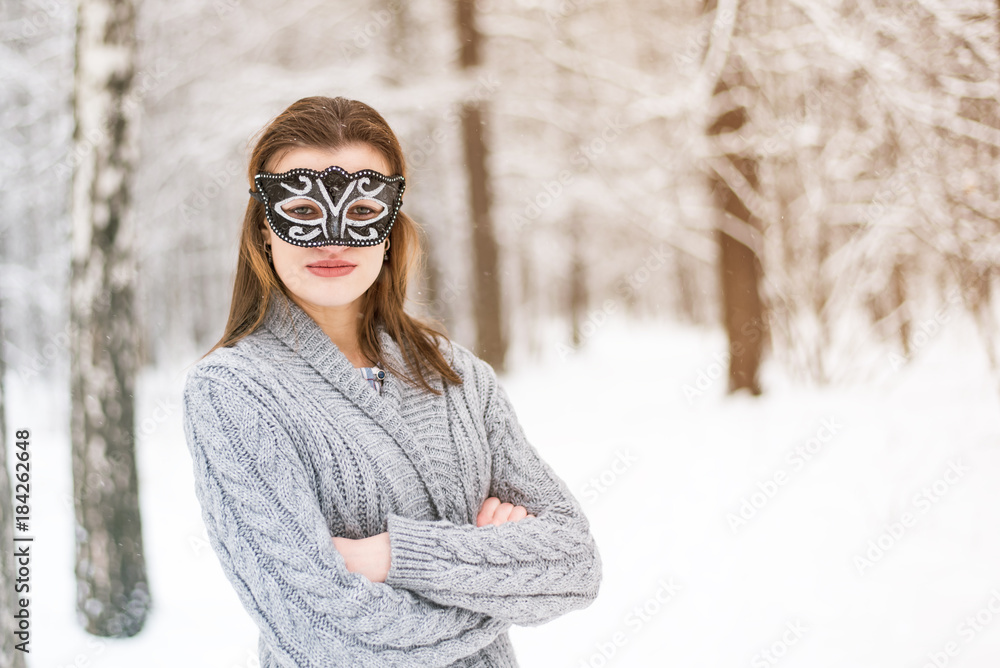 Beautiful young woman in carnival mask in winter forest Beautiful young woman in carnival mask in winter forest
