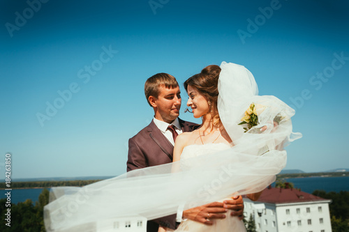 young bride and groom couple on the sky background photo