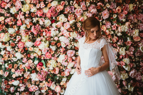 beautiful bride on the background of a wall of flowers