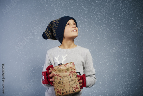 Boy with gift box looking at snow .