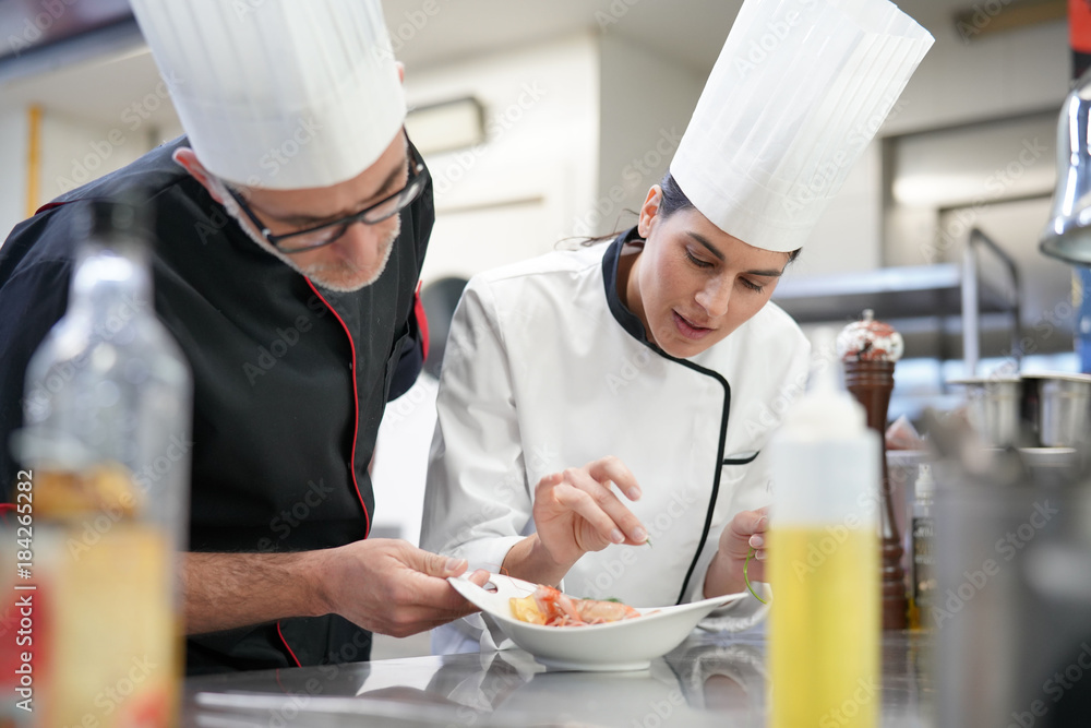 Professional cook chefs in kitchen improving dish composition Professional cook chefs in kitchen improving dish composition