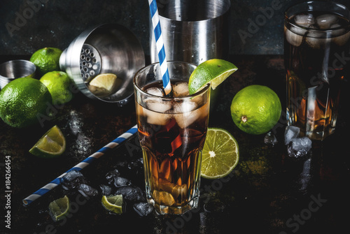 Cuba Libre, long island or iced tea cocktail with strong alcohol, cola, lime and ice, two glass, dark background copy space