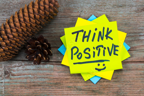 think positive - inspirational handwriting in a green sticky note  and  pine cones on wooden background photo