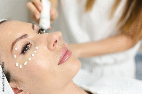Cosmetologist during anti age treatment on patient face