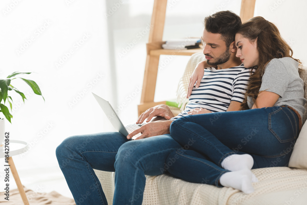 loving woman embracing her boyfriend while he working with laptop at home loving woman embracing her boyfriend while he working with laptop at home