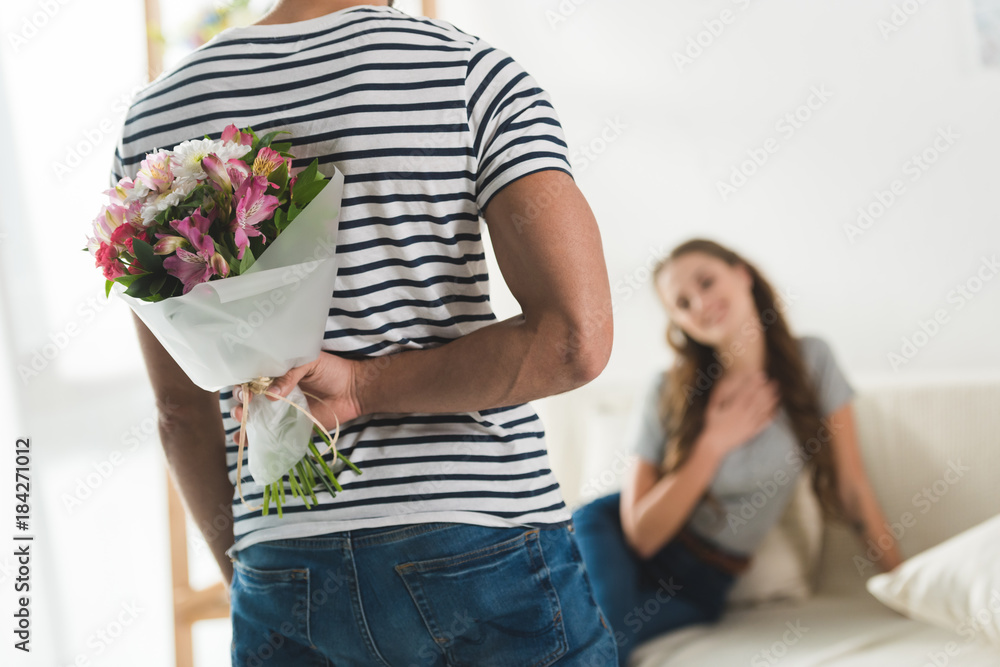 cropped shot of young man hiding bouquet behind back to present it to girlfriend cropped shot of young man hiding bouquet behind back to present it to girlfriend
