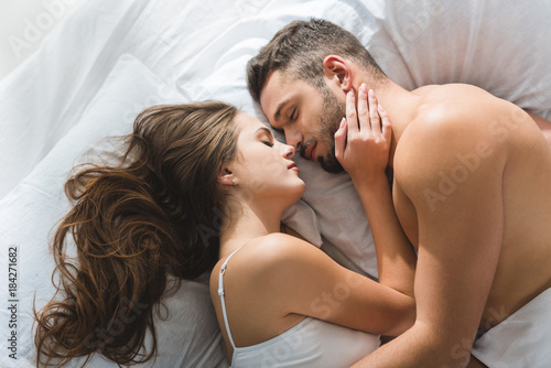 Obraz na plátne top view of young couple cuddling in bed in morning