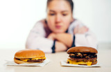 girl and two burgers, girl blurred in the background looking at two burgers in the foreground